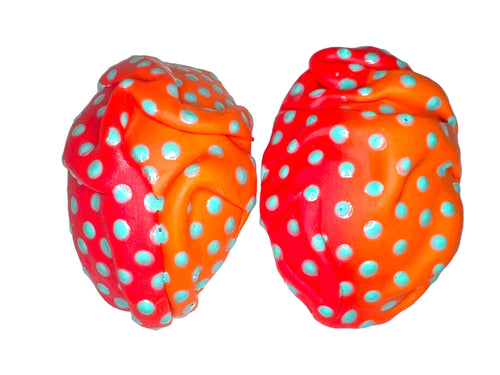 a pair of orange and blue polka dot covered earrings